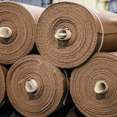 Rotoli di tessuto marrone impilati per lo stoccaggio e la successiva lavorazione