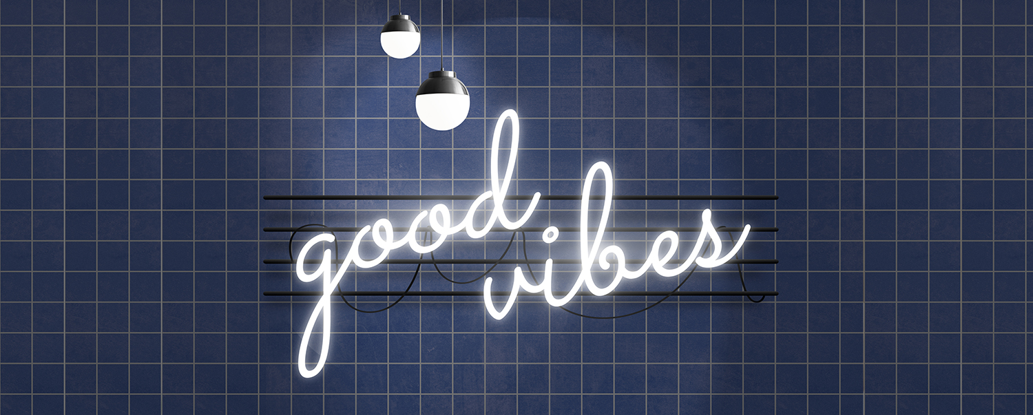 Insegna luminosa Good Vibes su sfondo blu, esempio di comunicazione visiva per merchandising.