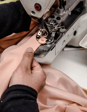 Mani di un operatore durante la cucitura di un tessuto con macchina professionale