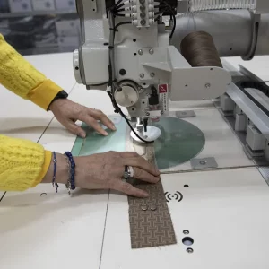 Cucitura di un campione di tessuto marrone con macchina da cucire industriale
