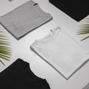 T-shirt grigia, bianca e nera piegate e disposte su una superficie chiara