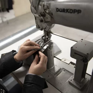 Lavorazione sartoriale con macchina da cucire industriale e regolazione del tessuto
