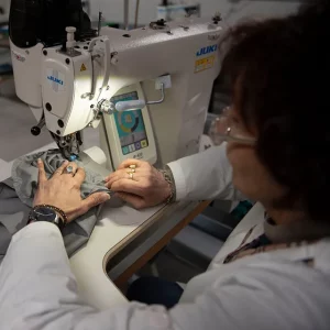 Operatrice al lavoro su una macchina da cucire industriale per la confezione di abbigliamento