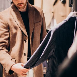 Professionista con cappotto sartoriale cammello durante la scelta di tessuti per abbigliamento maschile