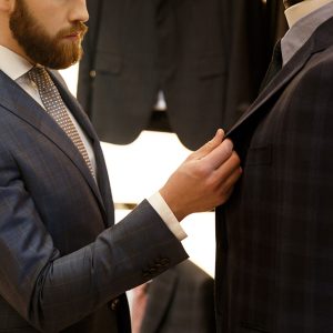 Uomo in completo elegante blu durante la valutazione di un tessuto sartoriale