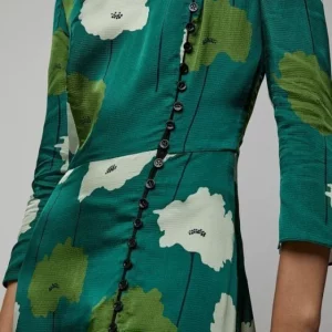 Dettaglio di abito verde con grandi fiori bianchi e bottoni