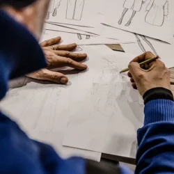 Designer al lavoro su disegni tecnici e bozzetti per la progettazione di abbigliamento