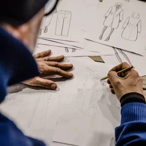 Designer al lavoro su schizzi tecnici per la progettazione di capi di abbigliamento